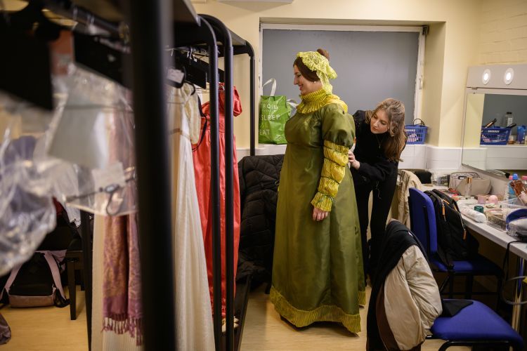 Tara assisting a cast member and adjusting their costume in the dressing room